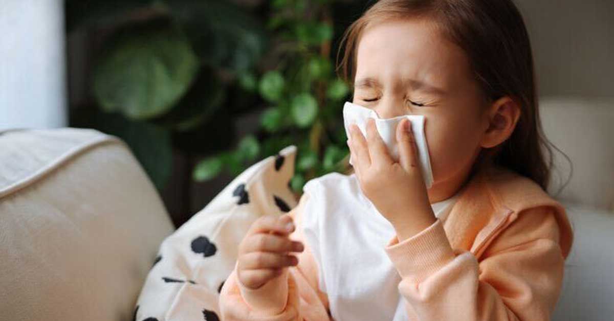 a child sneezing and covering her mouth with a handkerchief.
